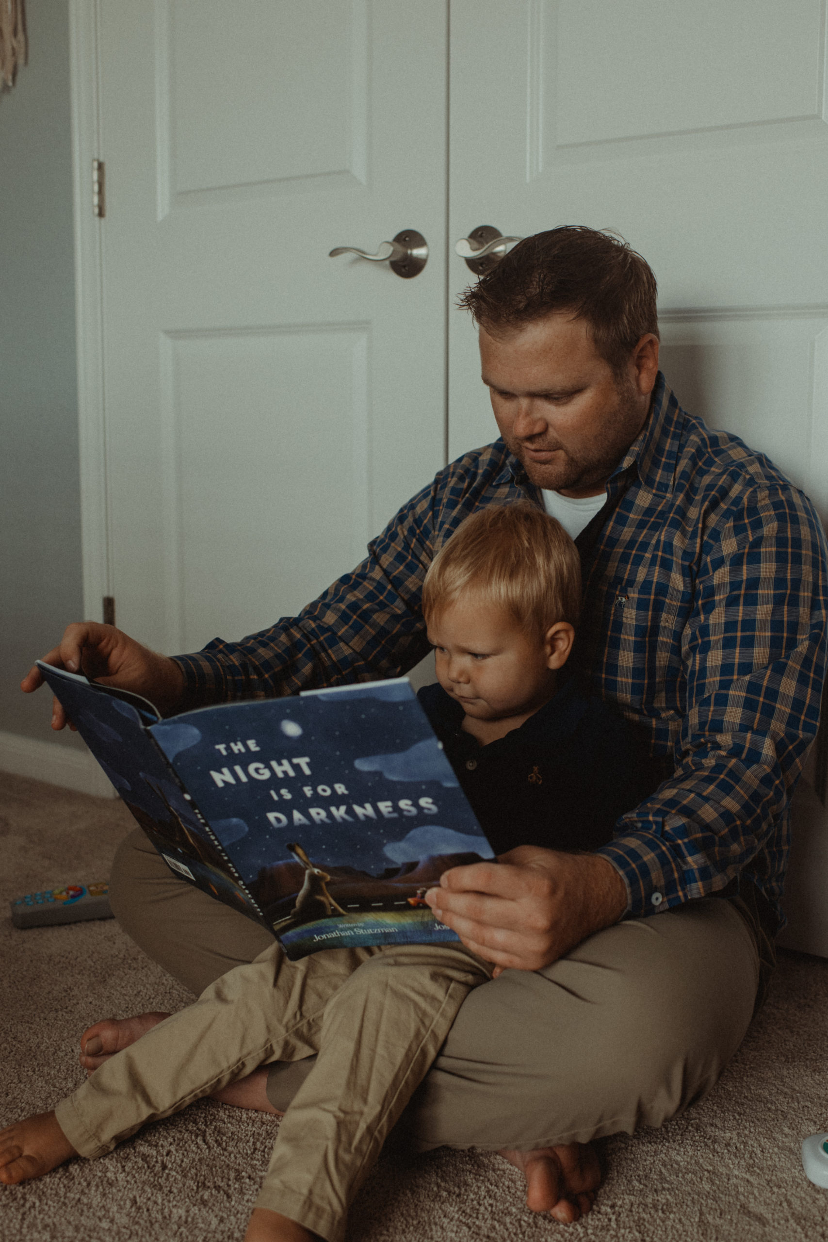 A dad reads his son a book in his bedroom by Meredith McCann Photography